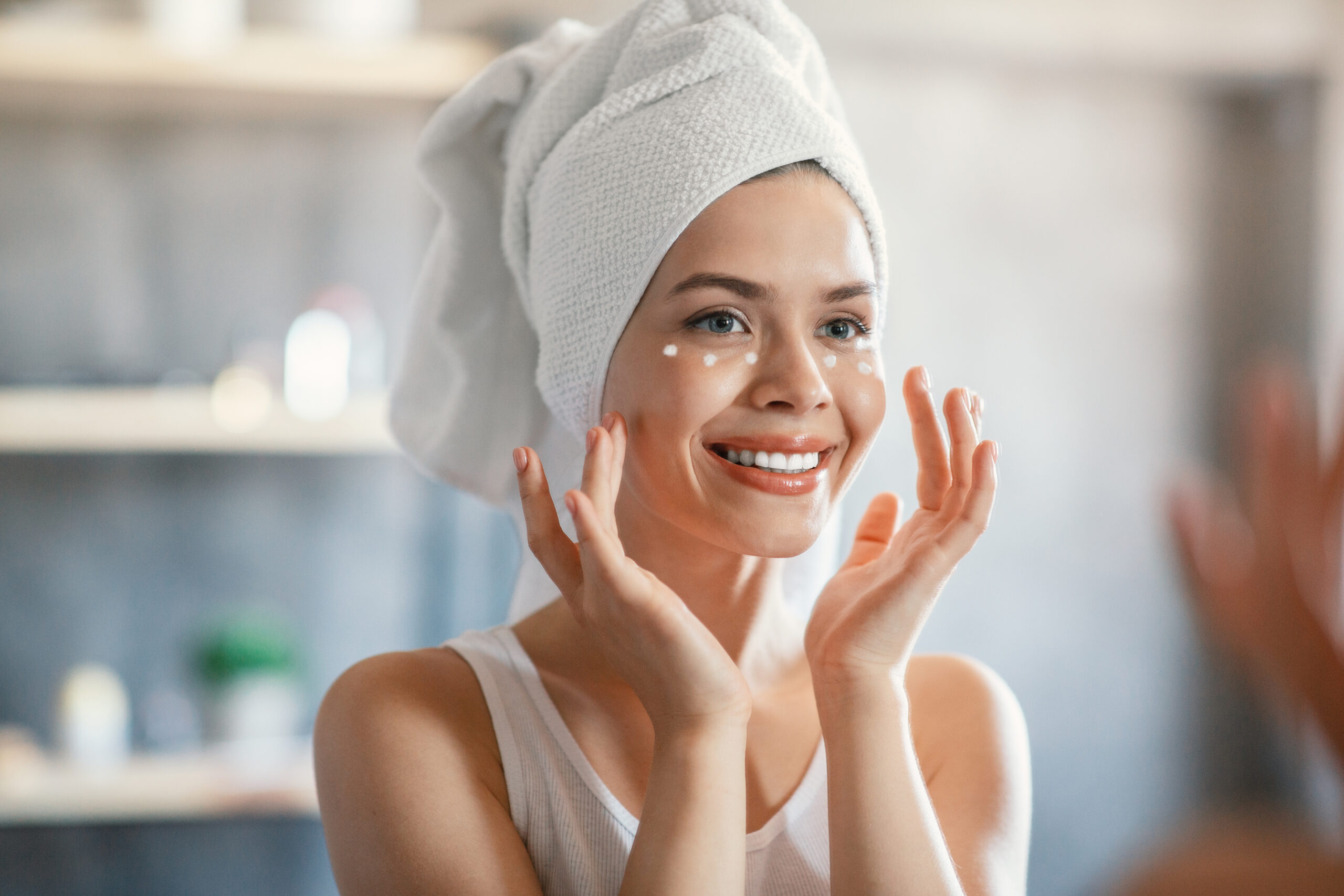Portrait of pretty lady applying cream under her eyes near mirror indoors Portrait of lovely lady applying cream under her eyes near mirror indoors